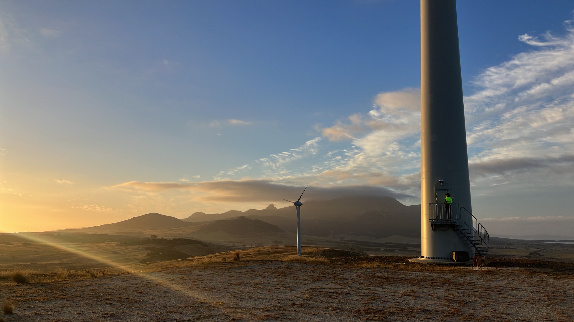 Wind turbines in an open field at sunset